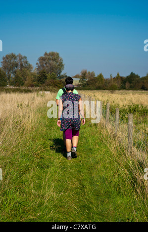 Vue arrière d'un jeune couple de randonneurs marcheurs marcher sur un sentier à travers la campagne du Sussex de l'Est Angleterre UK Banque D'Images