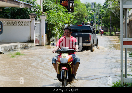 Smiling man on motorcycle durs le long de la rue inondée de soleil à Koh Klang à Chiang Mai Thaïlande Banque D'Images