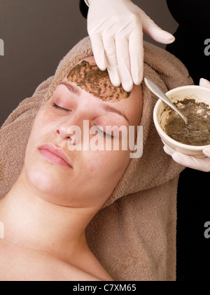 Femme avec les yeux fermés tout en masque peeling chinois des herbes et des algues Les algues est appliqué sur son visage Banque D'Images