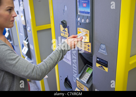 Femme de payer pour le stationnement à un ticket machine dans un parking Banque D'Images