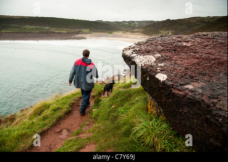 Un homme qui marche avec son chien le long du sentier côtier du parc national du Pembrokeshire, Pays de Galles, Royaume-Uni Manorbier Banque D'Images