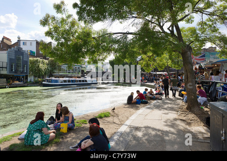 Les jeunes gens assis le long des rives de la Regent's Canal à Camden Lock, au nord de Londres, Angleterre, RU Banque D'Images