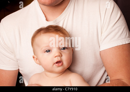 Jeune papa en plain white shirt with baby girl sur fond noir Banque D'Images