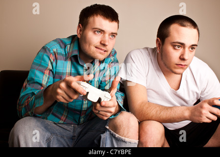 Deux beaux gars se concentrant tout en jouant les jeux vidéos Banque D'Images