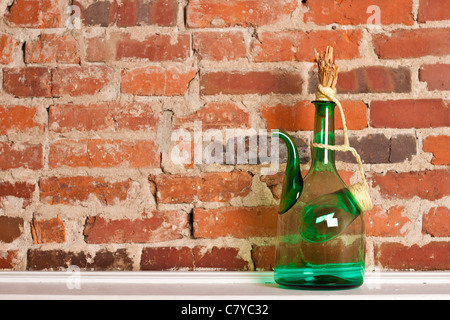 Verre vert cruche de vin sur la surface blanche contre brick wall Banque D'Images