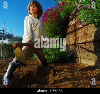 Petit garçon avec hoe comme travailleur russe soviétique URSS hero creuser le jardin dans la campagne près de Barcelone, en Espagne. Banque D'Images