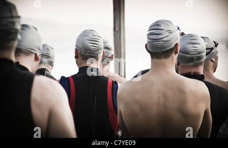 Les hommes attendent le début d'un triathlon vus de derrière eux. Banque D'Images