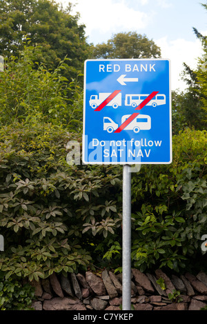 Un panneau routier dans un village rural waring de grands véhicules de ne pas suivre les instructions de navigation d'utiliser un inapte country road Banque D'Images