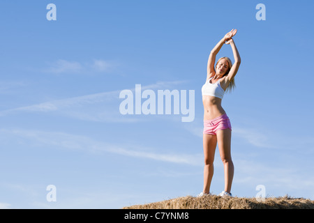 Femme active d'été qui s'étend sur balles en tenue de remise en forme Banque D'Images