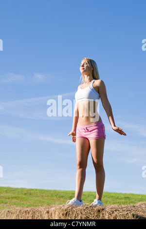 Femme active d'été qui s'étend sur balles en tenue de remise en forme Banque D'Images