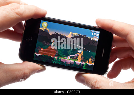 Mains tenant un vieil iPhone 2009 jouant le jeu Angry Birds - 2011 Banque D'Images