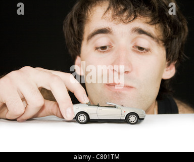 Jeune homme avec de l'argent voiture jouet. L'accent sur voiture. Banque D'Images