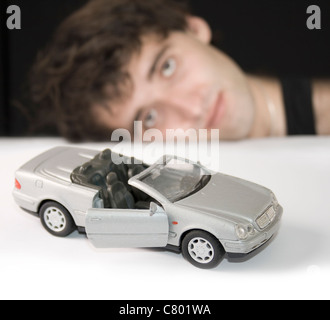 Jeune homme avec de l'argent voiture jouet. L'accent sur voiture. Banque D'Images