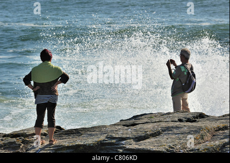 Les touristes à la recherche sur les vagues se briser sur les rochers à la Pointe Saint-Gildas / Saint Gildas Point, Loire-Atlantique, France Banque D'Images