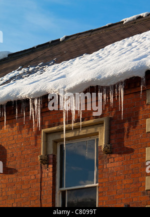 Glaçons pendant de gouttières sur la maison pendant une période de temps rigoureux de l'hiver Banque D'Images