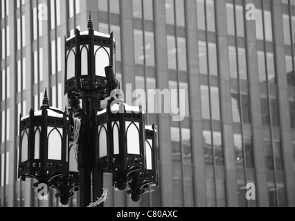 Photographie en noir et blanc d'un lampadaire en fer dans le centre-ville historique de Montréal, Québec, Canada, sky scrapper en arrière-plan. Banque D'Images