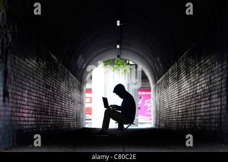 En informatique, hacker, siège de conspirateur, dans un tunnel, avec un ordinateur portable. Photo symbole, de la criminalité sur Internet. Banque D'Images