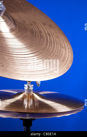 Un ensemble de cymbales tambour isolés contre un fond bleu dans le format vertical. Banque D'Images