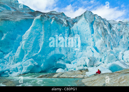 Norvège Nigardsbreen femme glacier en manteau rouge assis par Nigardsbreen bras du glacier Jostedalsbreen Sogn og Fjordane Europe occidentale de la Norvège UE Banque D'Images