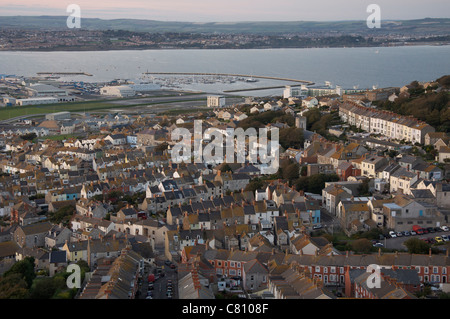 Donnant sur les toits de Fortuneswell sur l'Île de Portland, avec le port de Portland et partie de Weymouth au loin. Dorset, Angleterre, Royaume-Uni. Banque D'Images