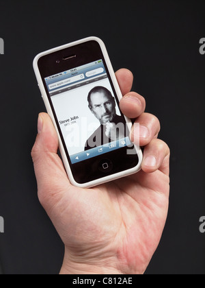 Page d'accueil Apple avec Steve Jobs in memoriam le jour où il est mort, il est indiqué sur un iPhone 4 dans la main. Banque D'Images