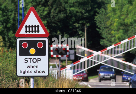 Passage à niveau par d'attente des voitures comme des lumières flash et descendre les barrières d'avertissement approche d'un train près de Leeds Yorkshire UK Banque D'Images