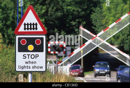 Passage à niveau par d'attente des voitures comme des lumières flash et descendre les barrières d'avertissement approche d'un train près de Leeds Yorkshire UK Banque D'Images