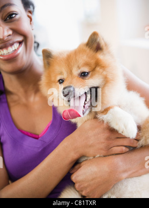 Mixed Race woman holding chien Pomeranian Banque D'Images