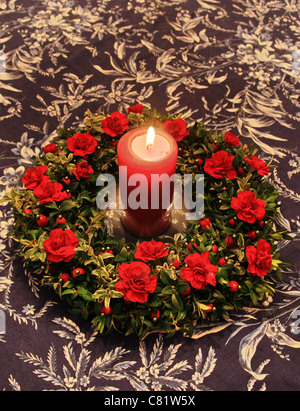 Bougie rouge entourée de décoration rouge et vert sur un dessus de table Banque D'Images