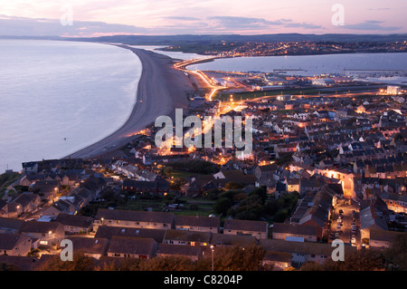 Le scintillement des lumières de Fortuneswell sur l'Île de Portland. Au loin s'étire Chesil Beach et la flotte. Dorset, Angleterre, Royaume-Uni. Banque D'Images