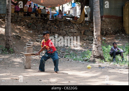 Les garçons à jouer au cricket indien sous les palmiers dans la ville de l'Inde rurale de Puttaparthi, Andhra Pradesh, Inde Banque D'Images