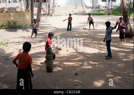 Les garçons à jouer au cricket indien sous les palmiers dans la ville de l'Inde rurale de Puttaparthi, Andhra Pradesh, Inde Banque D'Images