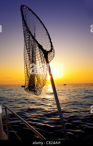 Dans l'épuisette pêche bateau sur l'horizon de l'eau lever du soleil Banque D'Images