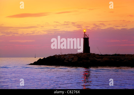 Lever du soleil rougeoyant phare dans la mer pourpre bleu et orange sky Banque D'Images