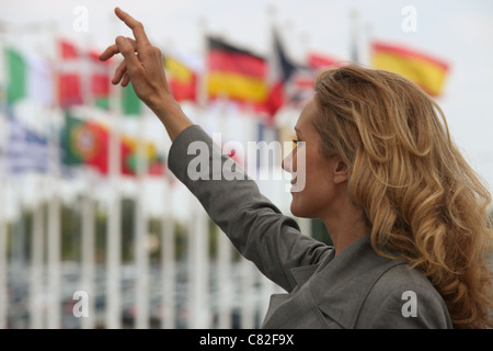 Woman hailing taxi en face de drapeaux internationaux Banque D'Images