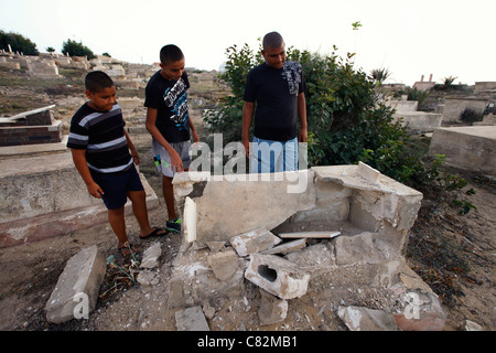 De jeunes Arabes israéliens font une enquête sur une tombe musulmane profanée par une attaque apparente à prix réduit au cimetière musulman d'al-Kazakhana à Jaffa, un quartier juif arabe mixte en Israël. Le terme « Prix » est utilisé pour désigner les actes de violence politique commis par des Israéliens de droite protestant contre la politique du gouvernement israélien concernant les colonies et les Palestiniens. Banque D'Images