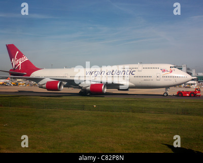 Les voyages aériens et l'environnement. Virgin Atlantic Airways Boeing 747-400 à l'aéroport de Gatwick en remorque comme une alternative à la circulation au sol par ses propres moyens Banque D'Images