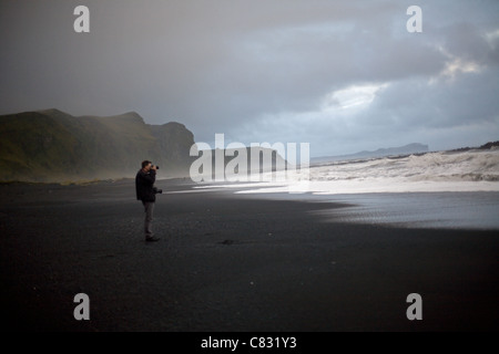 Un homme prend une photo sur la plage de Vik, Islande Banque D'Images