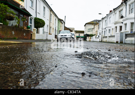 Fuite d'eau dans le milieu d'une rue résidentielle causé par une rafale d'eau principale. Banque D'Images