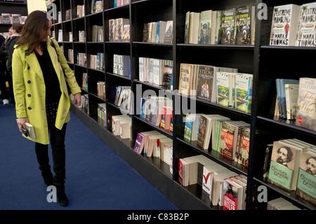 Une femme dans une librairie Waterstone's / tente, à la recherche et à la préparation à l'achat de livres à la Cheltenham Literature Festival. Banque D'Images