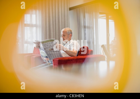 Man reading newspaper in armchair Banque D'Images