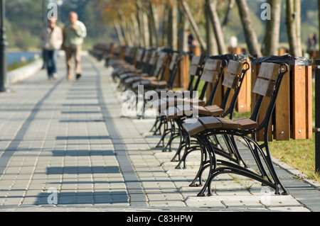 Promeneurs sur banc de la rangée Banque D'Images