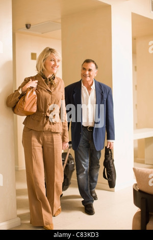 Vieux couple rolling luggage in walkway Banque D'Images