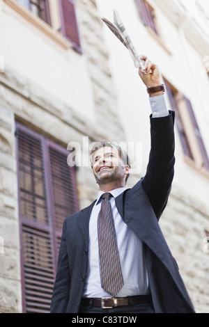 Businessman hailing taxi on city street Banque D'Images