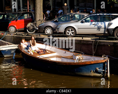 Deux jolies filles speding leur pause déjeuner au soleil sur un bateau sur un canal à Amsterdam, Pays-Bas Banque D'Images