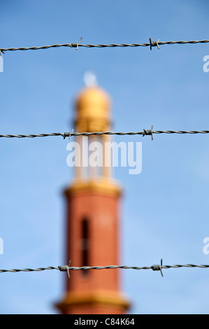 Les fils barbelés d'une grande netteté avec une mosquée du flou en arrière-plan Banque D'Images