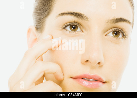 Woman applying undereye cream, close-up Banque D'Images