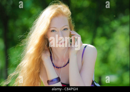 Portrait de jeune fille rousse de l'utilisation des écouteurs Banque D'Images