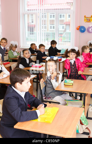 Les garçons et les filles russes blancs les élèves sont assis sur la leçon en classe à l'école au début septembre. Banque D'Images