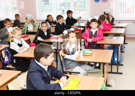 Les garçons et les filles russes blancs les élèves sont assis sur la leçon en classe à l'école au début septembre. Banque D'Images